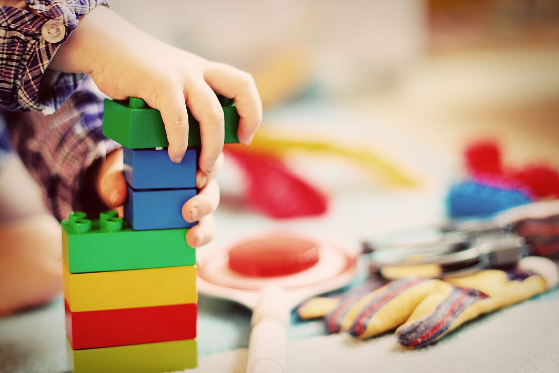 Ein Kind spielt mit Lego Duplo Spielblöcken in einem Kinderzimmer.