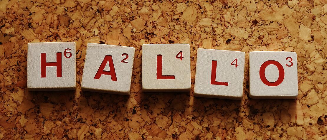 Das Wort "Hallo" buchstabiert mit hölzernen Spielsteinen.