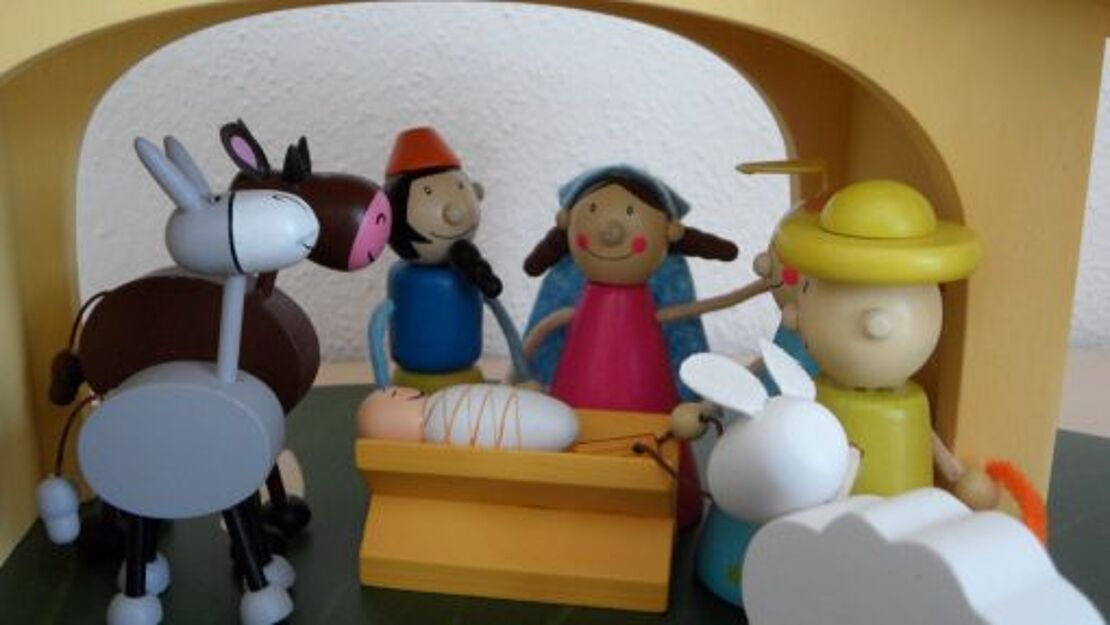 Mehrere kleine Figuren aus Holz beim Krippenspiel zur Geburt Jesu Christi.