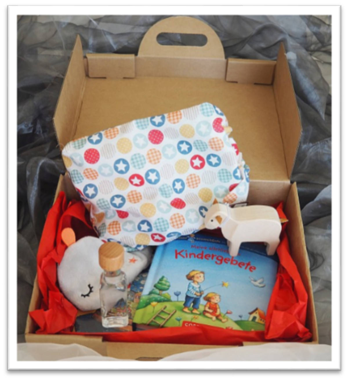 Ein Kartonpaket mit diversen Kinderspielzeugen wie beispielsweise ein Kinderbuch und ein Plüschtier verpackt.